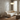 A modern floor lamp with a curved silver metal arm and a glowing oval shade stands beside a cream boucle sofa in a softly lit living room with wood floors and sheer curtains.